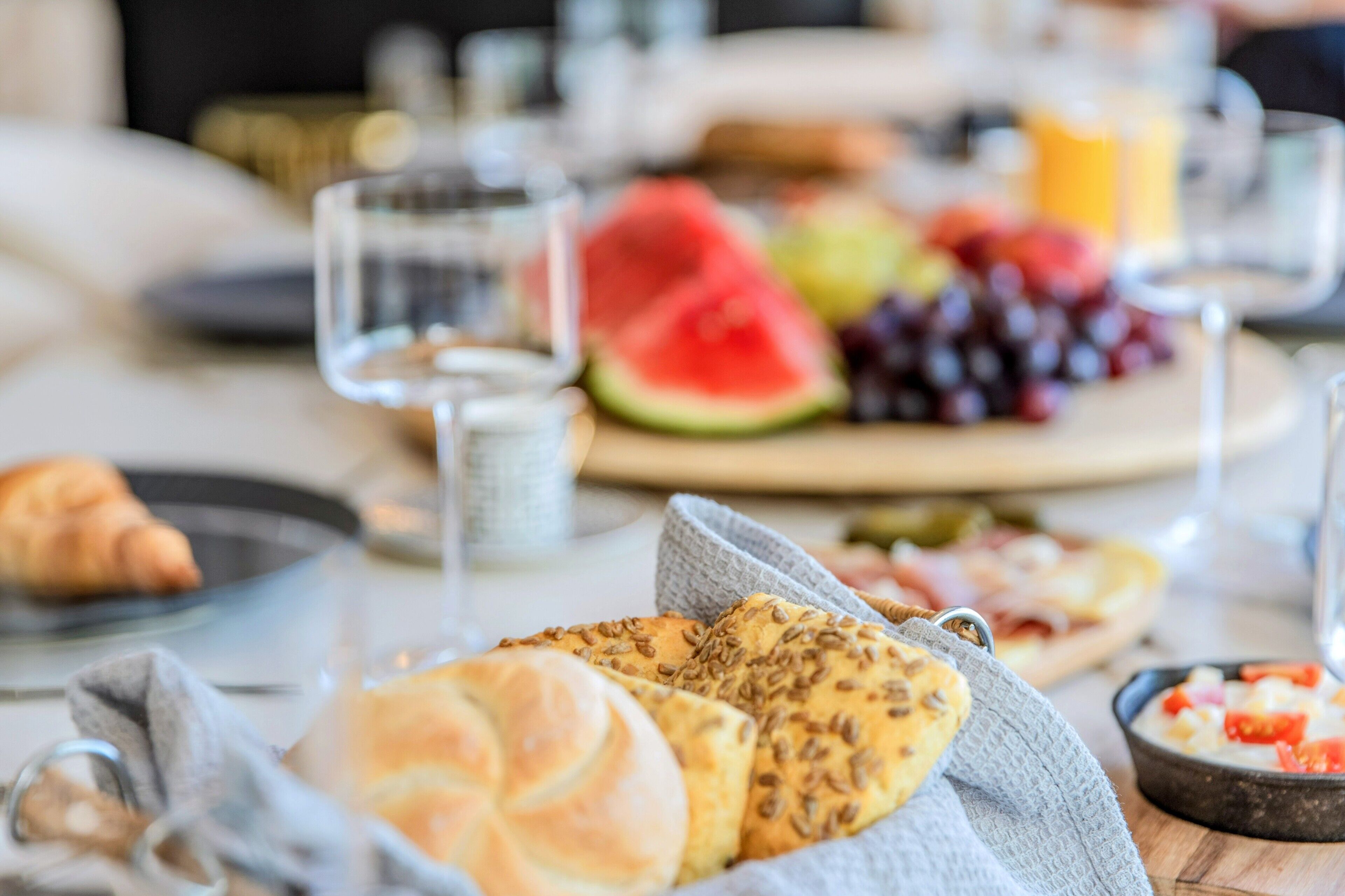 A breakfast setting with bread, fruits, and a bowl of soup.