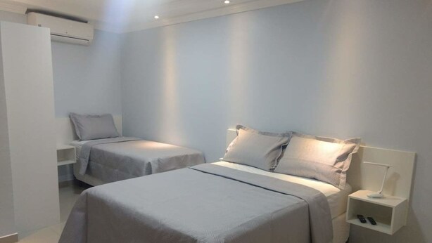 Una habitación de hotel con dos camas, una mesita de noche con lámpara y un armario.