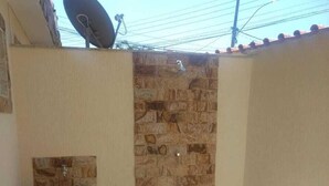 Un baño pequeño con pared de piedra, un lavamanos y una zona de ducha.
