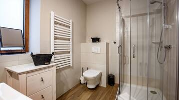 Un baño moderno con inodoro, bidé y ducha con mampara de vidrio.