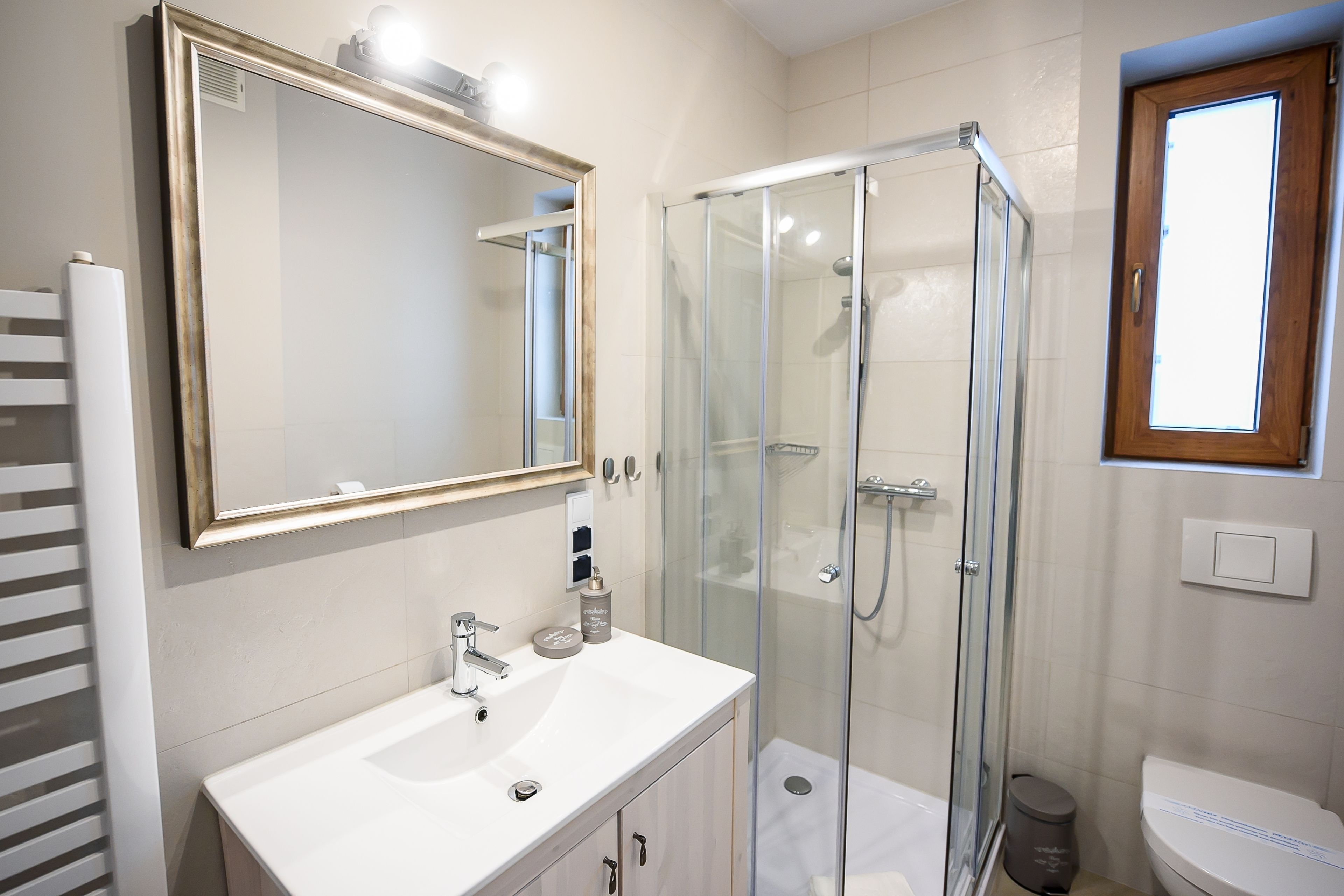 A modern bathroom with a glass-enclosed shower, a white sink, and a large mirror.