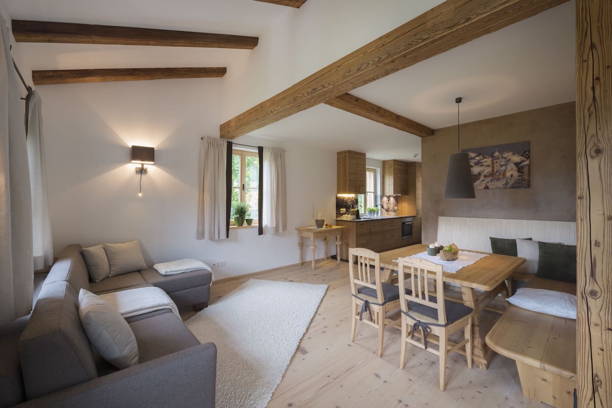 A cozy living room with a sofa, a dining table with chairs, and a kitchen in the background.