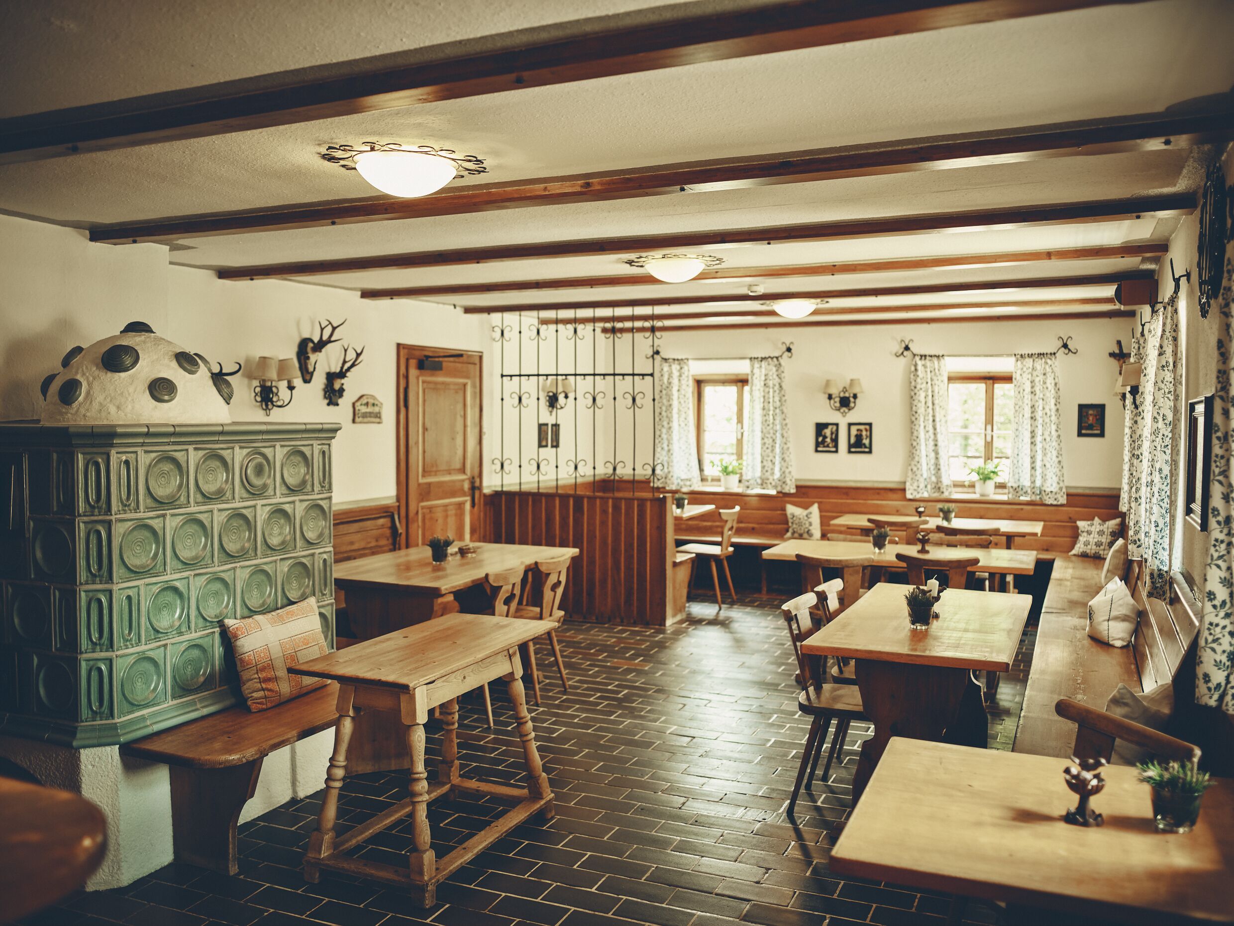 A traditional inn with wooden furniture, a tiled floor, and a rustic decor including a green cabinet and antlers on the wall.