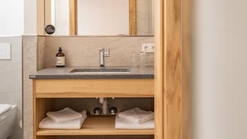 A modern bathroom with a wooden vanity, a mirror, and a sink.