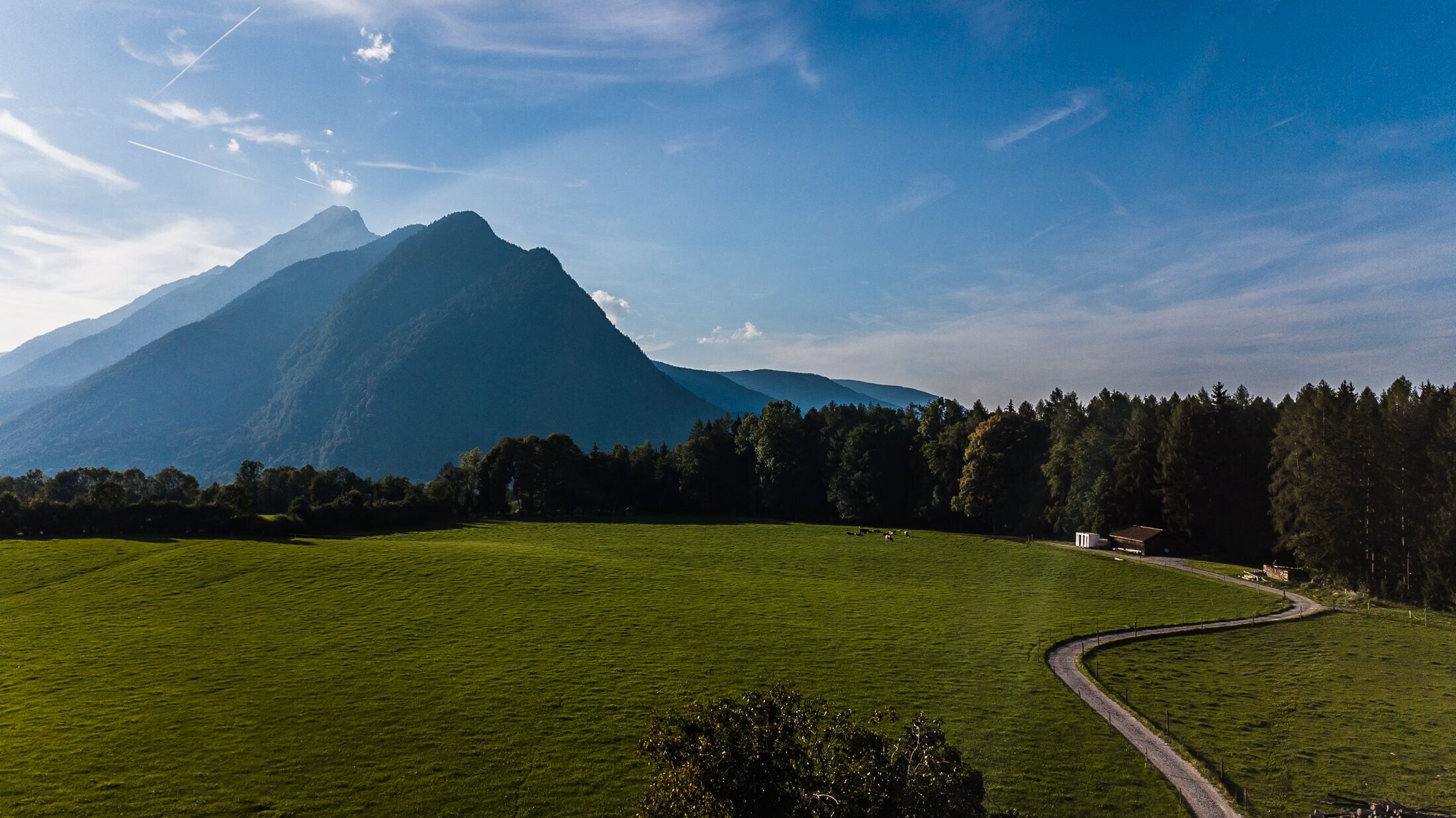 A mountainous landscape with a green field and a winding road.