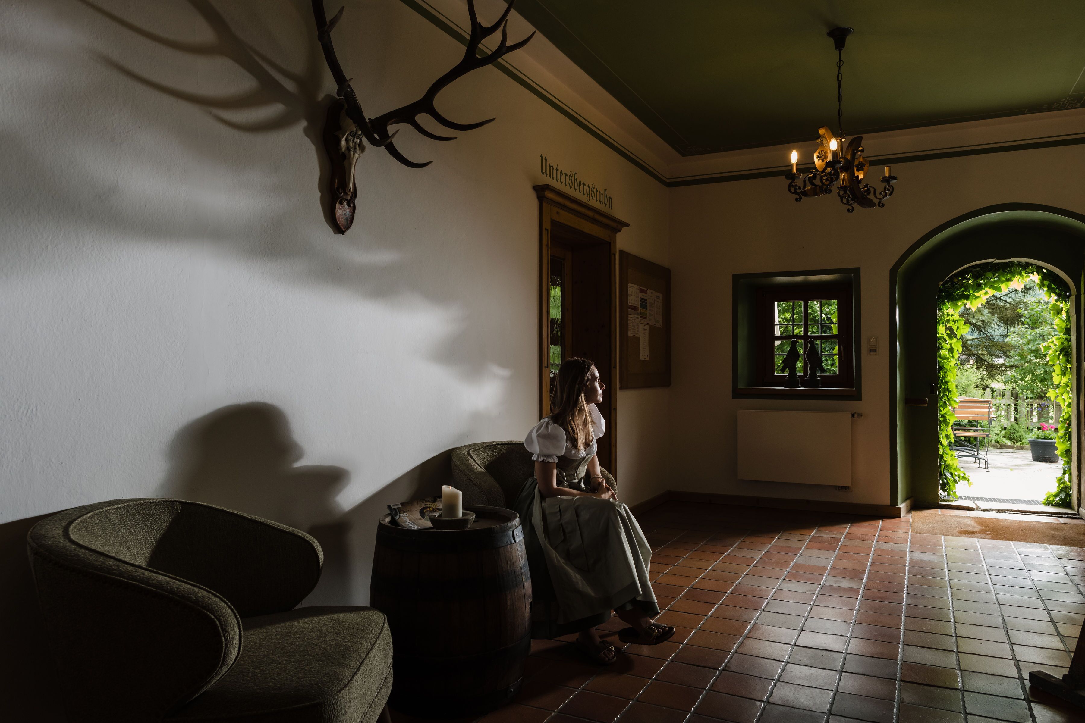 Una habitación con decoración rústica, que incluye una cabeza de venado en la pared, un barril de madera y un candelabro.