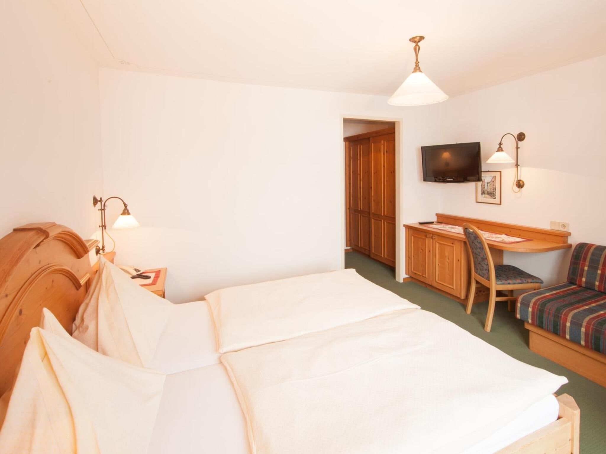 Ett hotellrum med en säng, ett skrivbord, en stol och en tv.