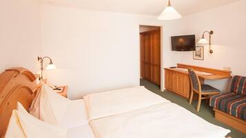 Ett hotellrum med en säng, ett skrivbord, en stol och en tv.