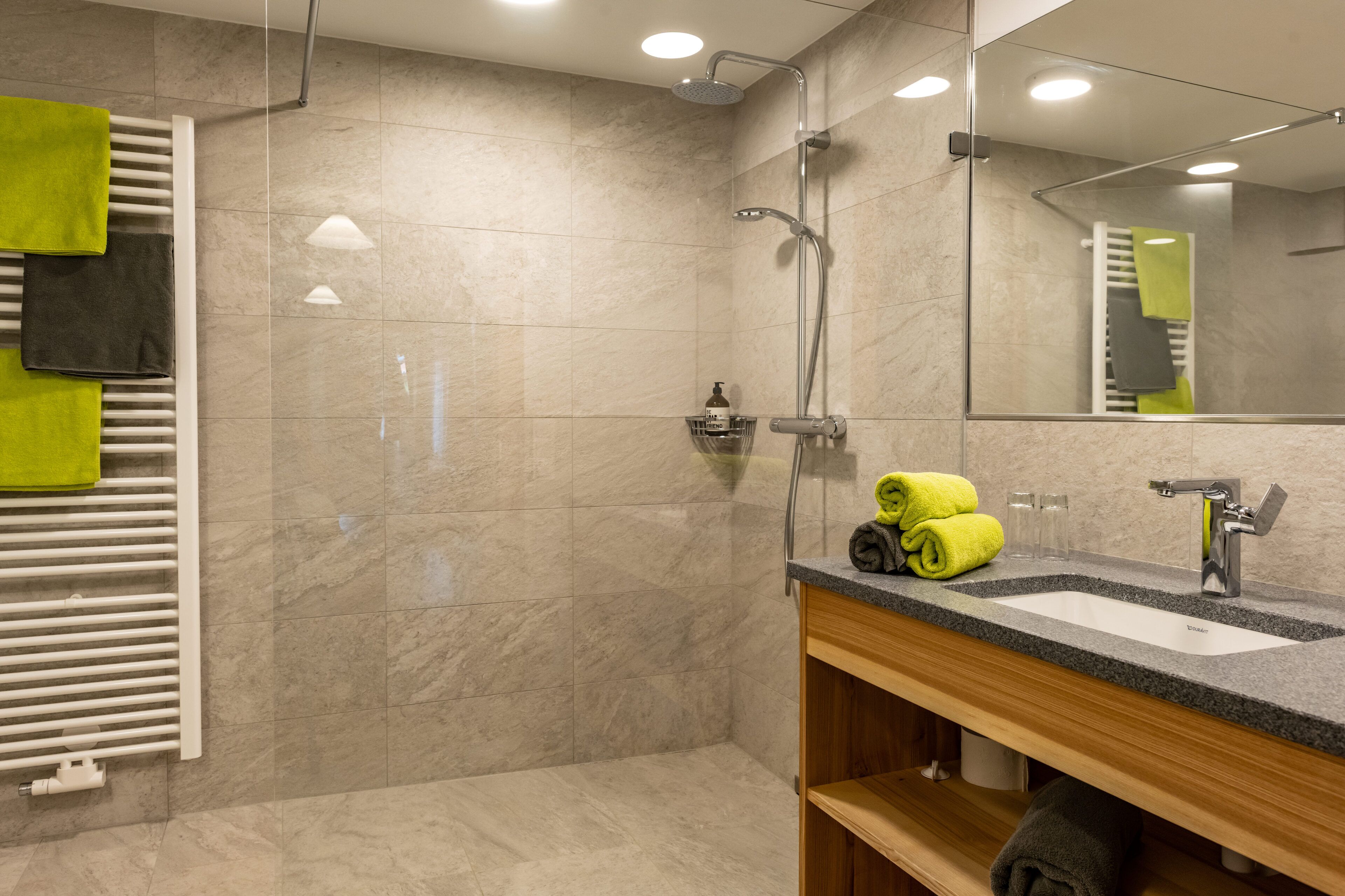 Un baño moderno con cabina de ducha de vidrio, lavamanos blanco y tocador de madera.