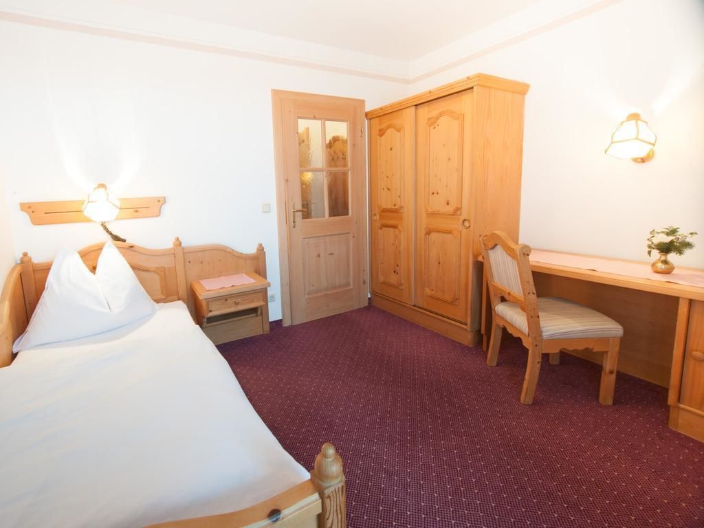 Habitació d'hotel amb un llit, una taula, una cadira, un armari i una porta.