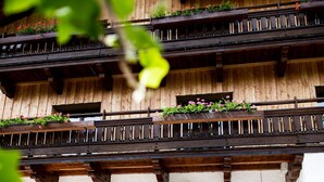 Ein traditionelles Holzgebäude mit Balkon, Holztischen und -stühlen sowie einem mit Efeu bewachsenen Bogen.