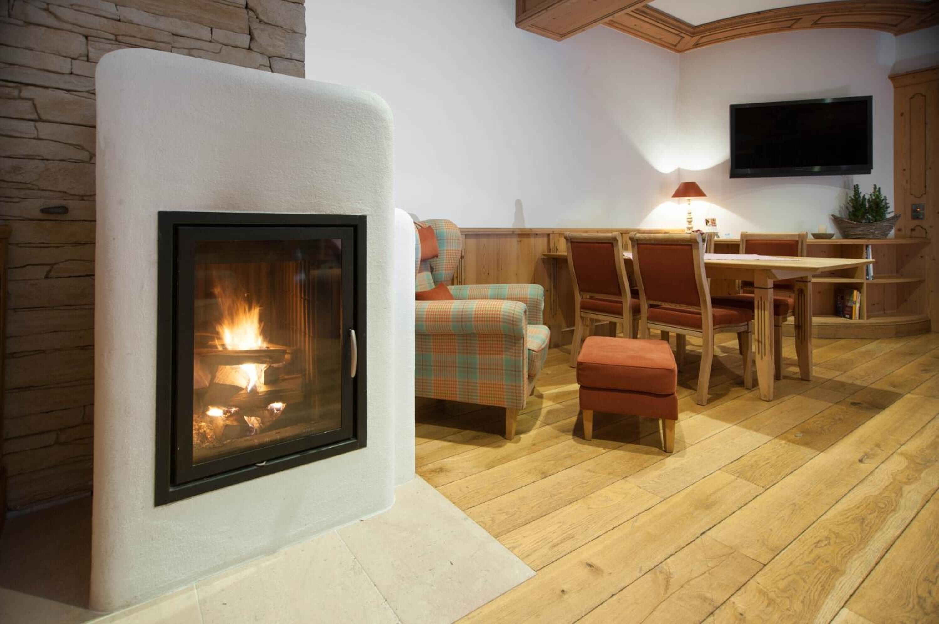 A cozy living room with a fireplace, a television mounted on the wall, and a dining area with wooden furniture.