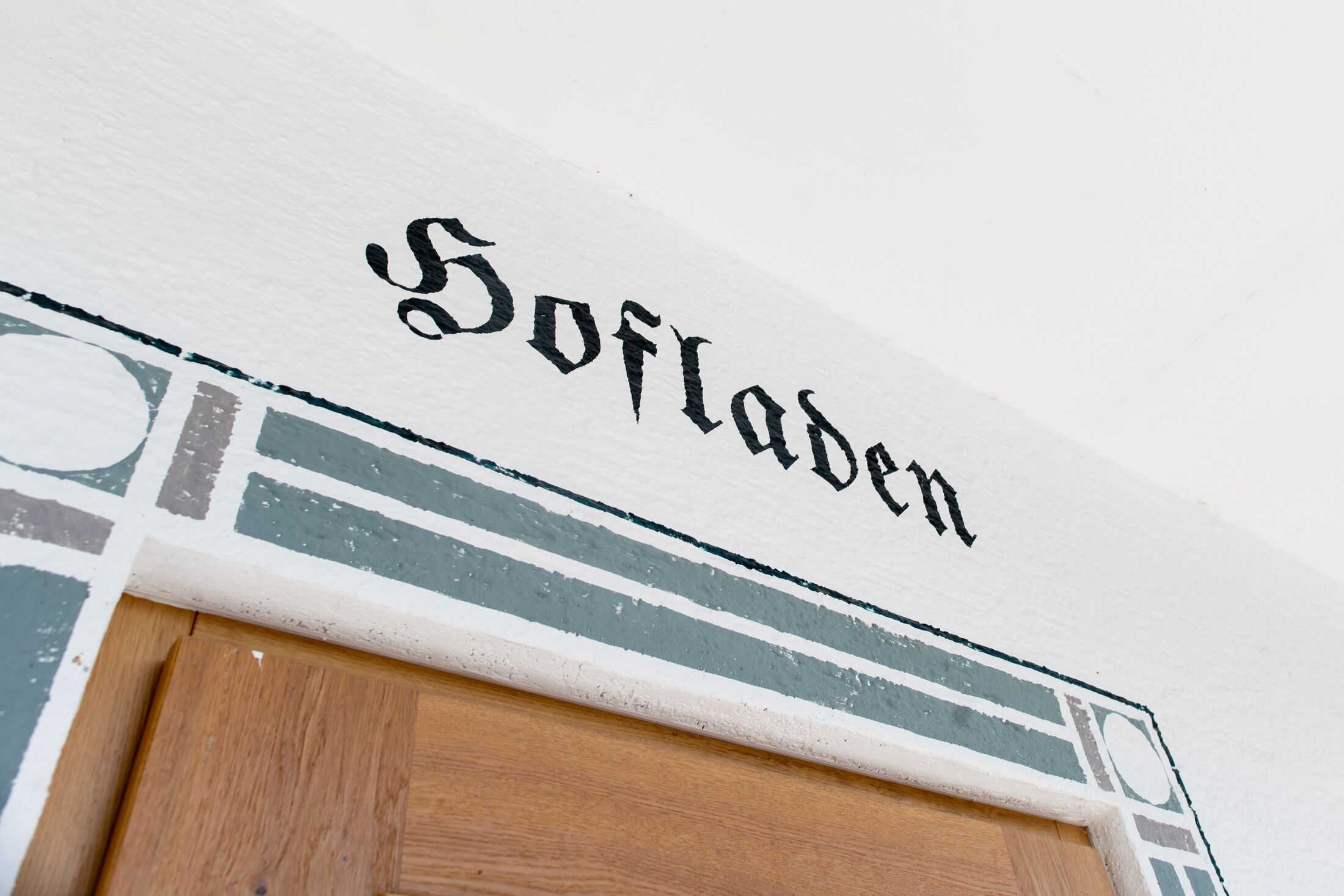 Paredes com o texto "Softladen" e uma porta de madeira abaixo.