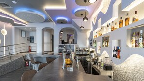 A modern bar area with a curved counter, seating, and a variety of bottles on shelves. - N E P center Hotel Rodos (Rhodes)