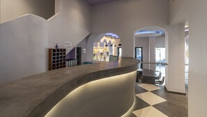 A modern reception area with a curved counter, a staircase, and a bar area with shelves. - N E P center Hotel Rodos (Rhodes)