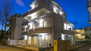 A multi-story residential building with balconies, a gated entrance, and a well-lit facade. - Residenza Riva Azzurra (Rimini)