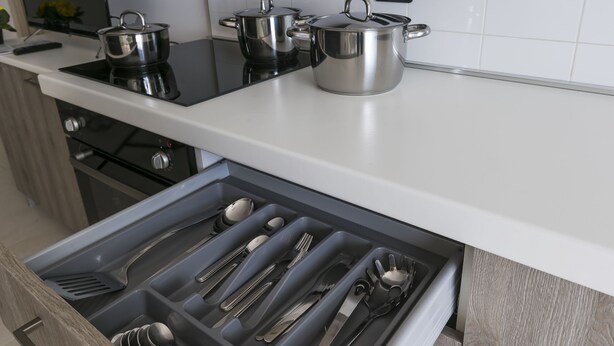 A kitchen with a white countertop, stainless steel pots, and a drawer with utensils. - Residenza Riva Azzurra (Rimini)