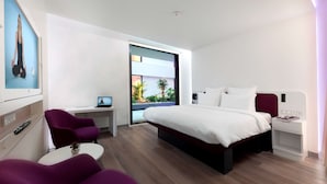 Een moderne hotelkamer met een groot bed, een bureau, een stoel en uitzicht op het landschap.