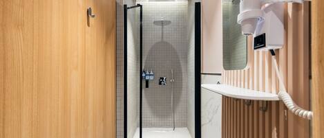 A modern bathroom with a glass-enclosed shower, a wooden vanity, and a marble-tiled floor.