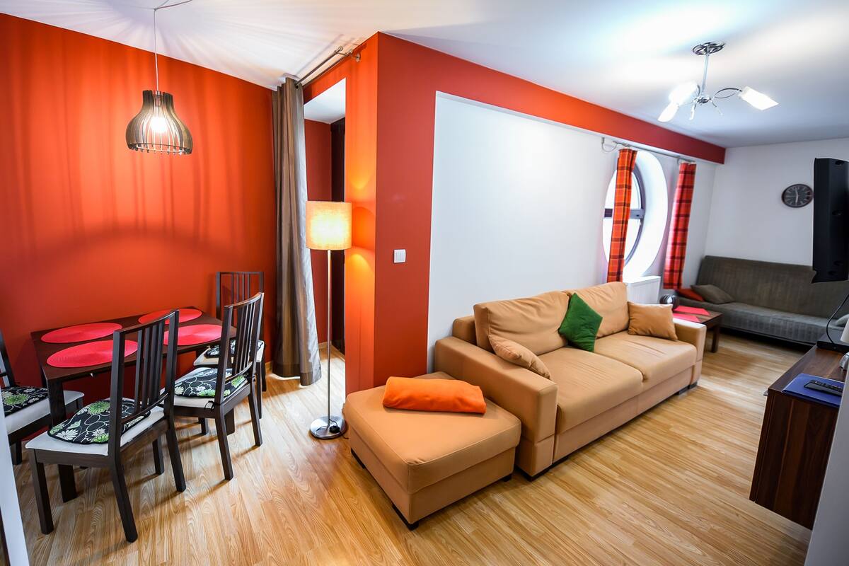 A modern living room with a sofa, ottoman, and dining table with chairs.