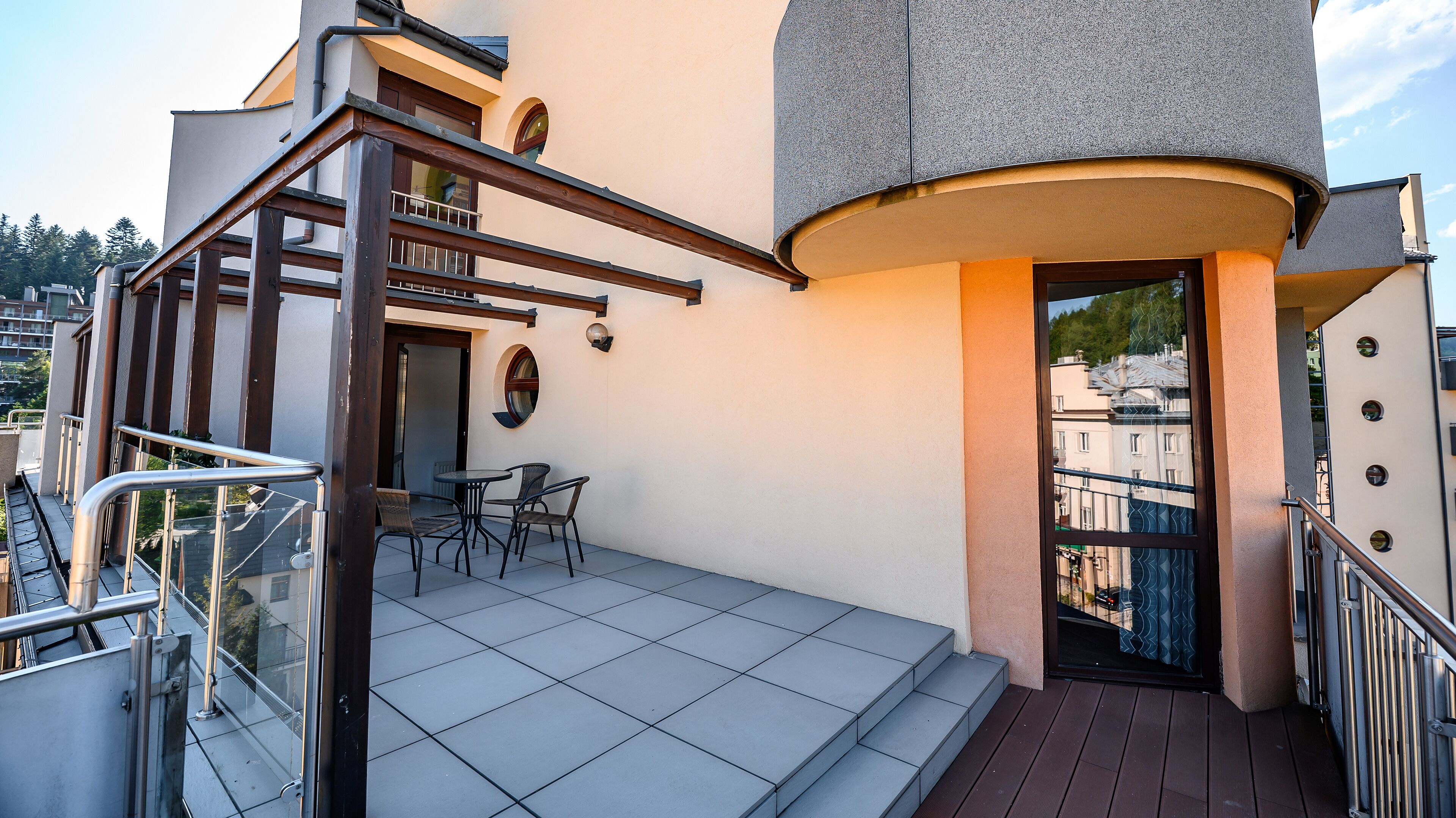 A balcony with a table and chairs, a door, and a view of the cityscape.
