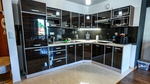 A modern kitchen with dark cabinetry, a stainless steel sink, and a built-in microwave. - Sun & Snow Centrum Piłsudskiego (Krynica-Zdroj)