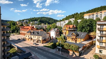Un pueblo con arquitectura europea tradicional, que incluye una mezcla de edificios residenciales y comerciales, una avenida principal y un paisaje montañoso de fondo.