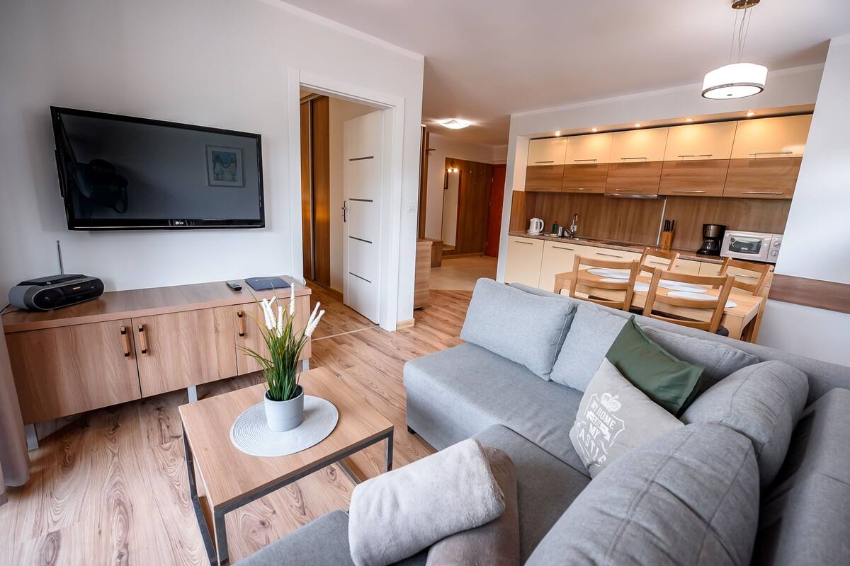 A modern living room with a flat-screen TV, a sofa, a coffee table, and a wooden cabinet.