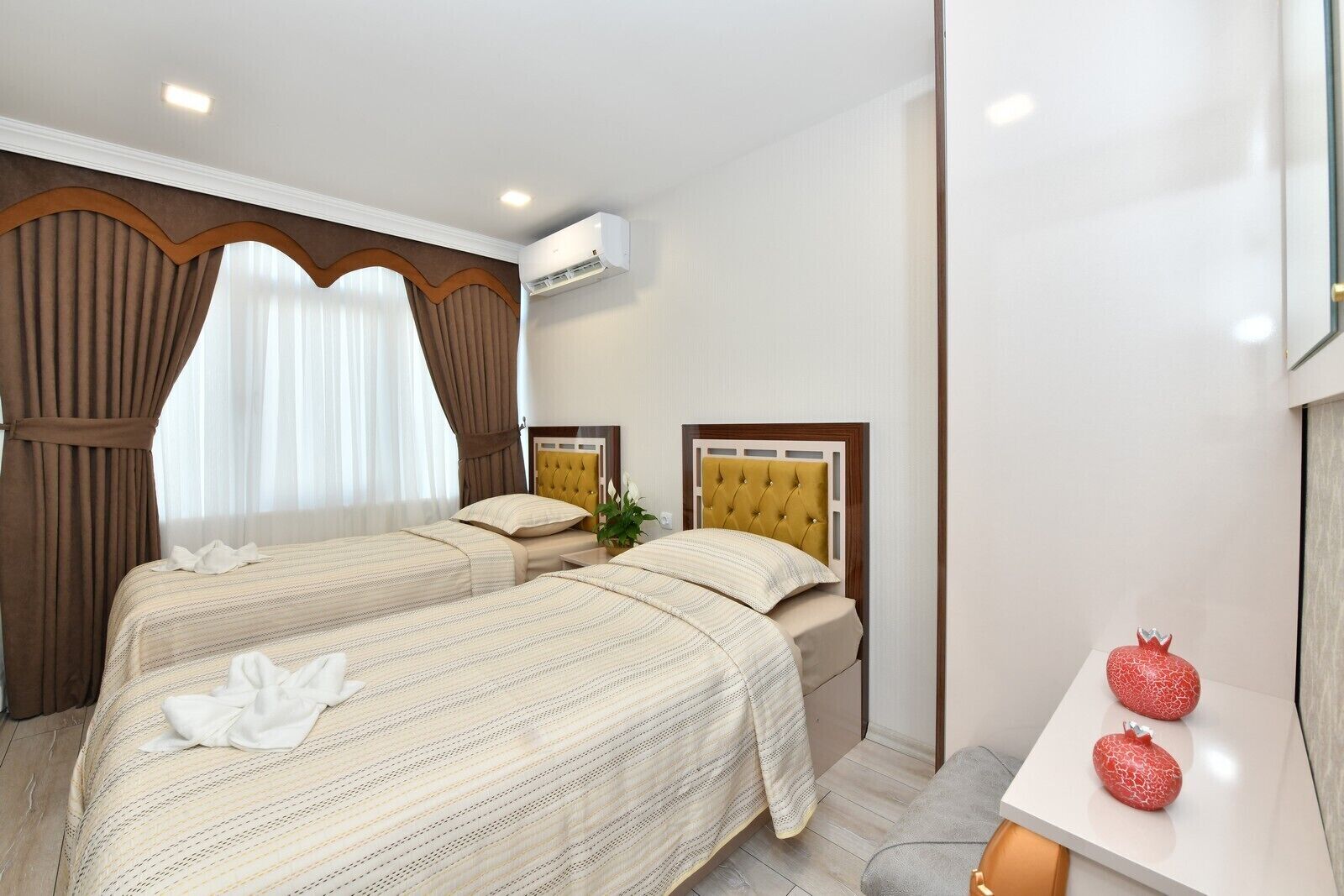 Une chambre d’hôtel avec deux lits, une plante en pot et une petite table agrémentée d’objets décoratifs.