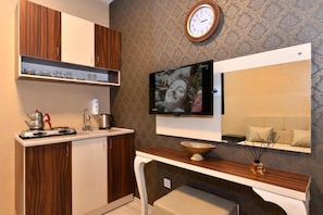 Una cucina moderna con mobili in legno, piano cottura integrato e TV a schermo piatto montata a parete.