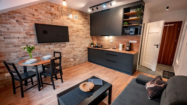A modern kitchen with dark cabinets, a built-in microwave, and a wooden countertop. - Apartamenty Sun & Snow Centrum Cicha (Krynica-Zdroj)
