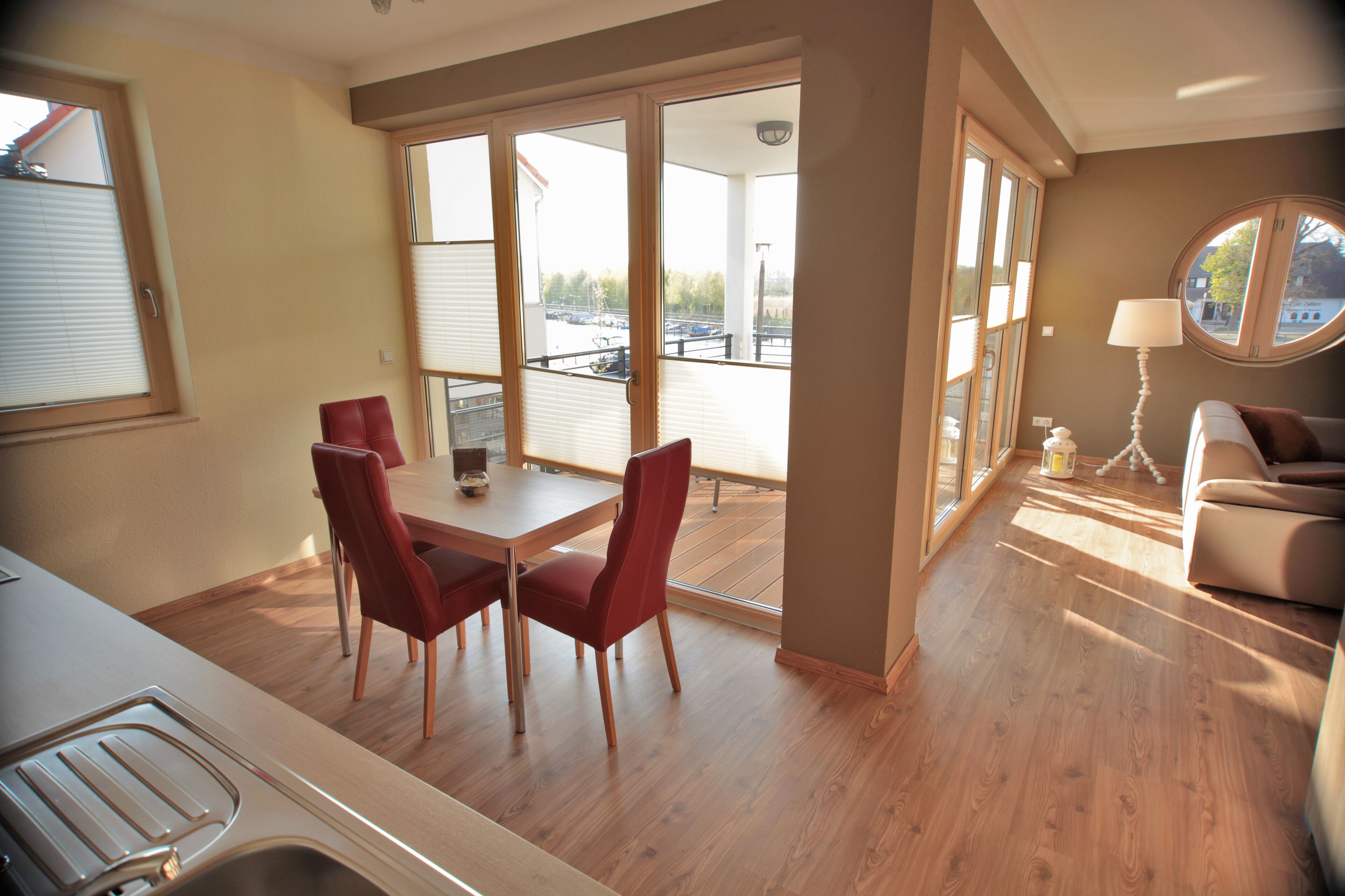 A modern living room with a dining area, large windows, and a view of the outside.