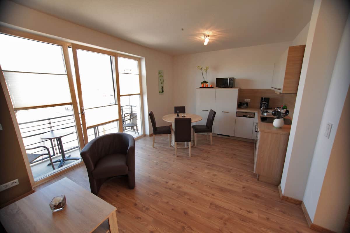 Un appartement moderne comprenant un coin repas, une cuisine et de grandes portes-fenêtres coulissantes donnant sur un balcon.