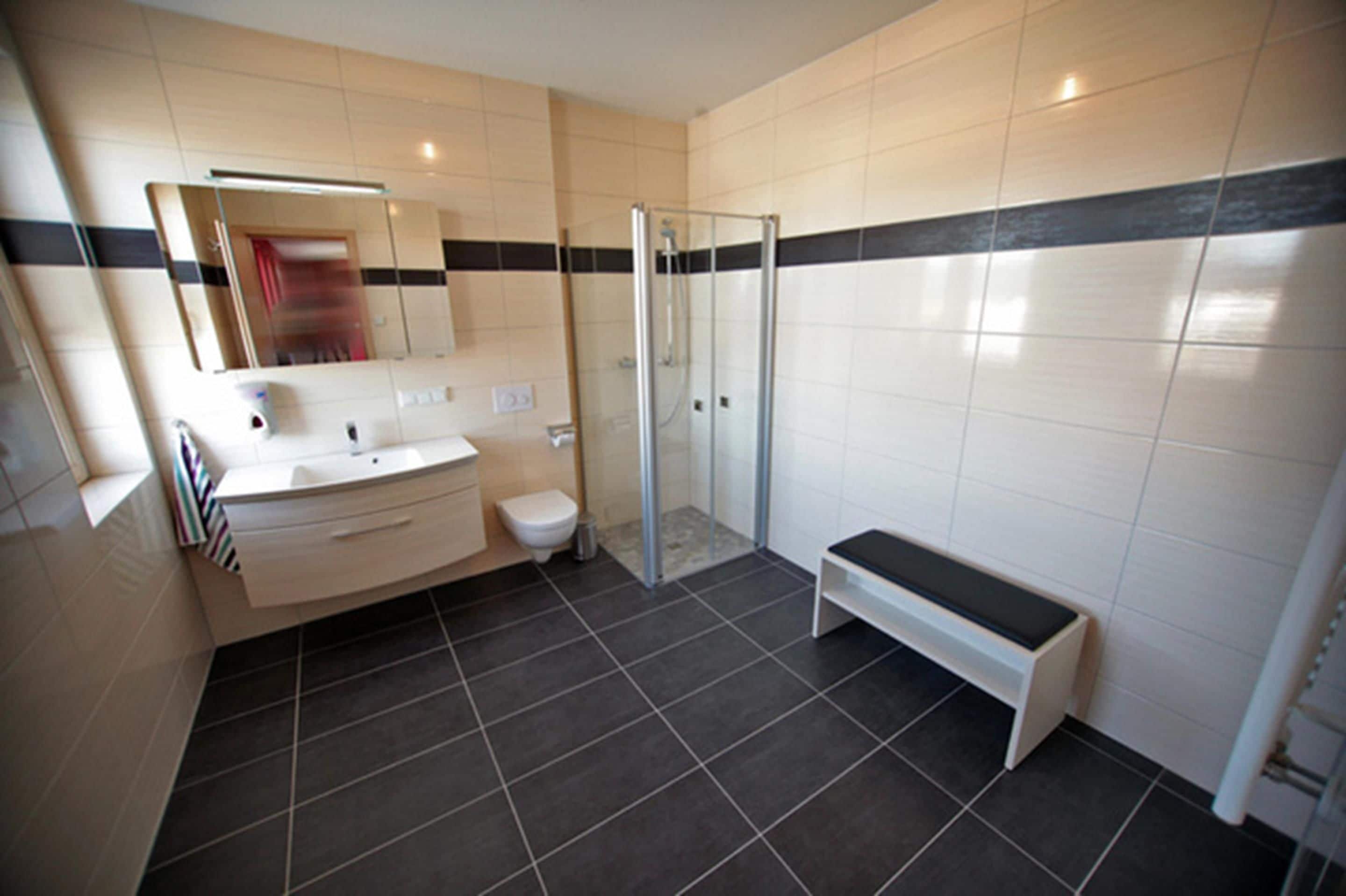 A modern bathroom with a shower, toilet, and vanity.