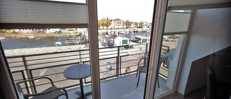 A balcony with a view of a marina, a table, and chairs.