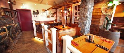 A restaurant with wooden tables and benches, stone walls, and a red door.