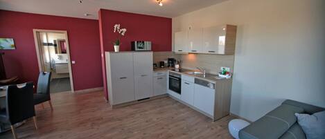 A compact living space with a kitchenette, dining area, and a sofa.