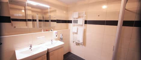 A bathroom with two sinks, a mirror, a towel rack, and a shower.