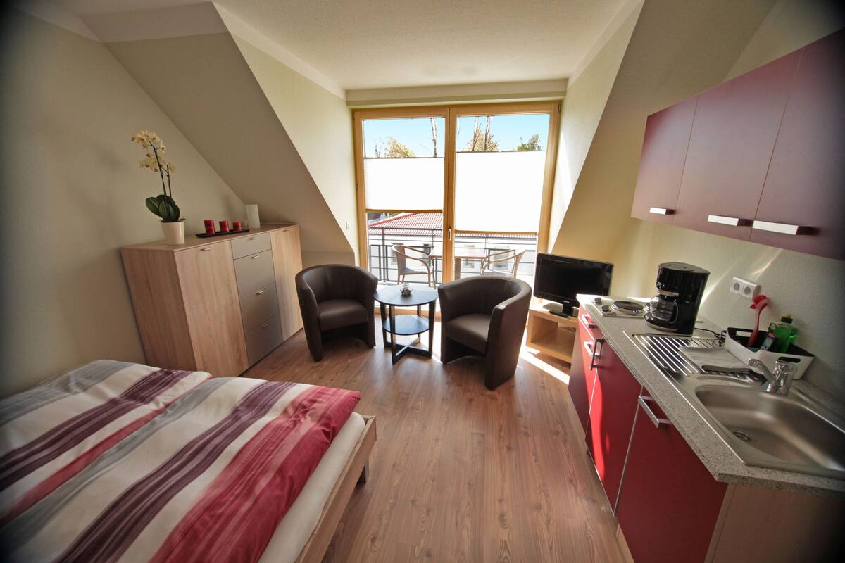 Une chambre à coucher avec un lit, un bureau et une chaise. Il y a une fenêtre donnant sur l’extérieur.