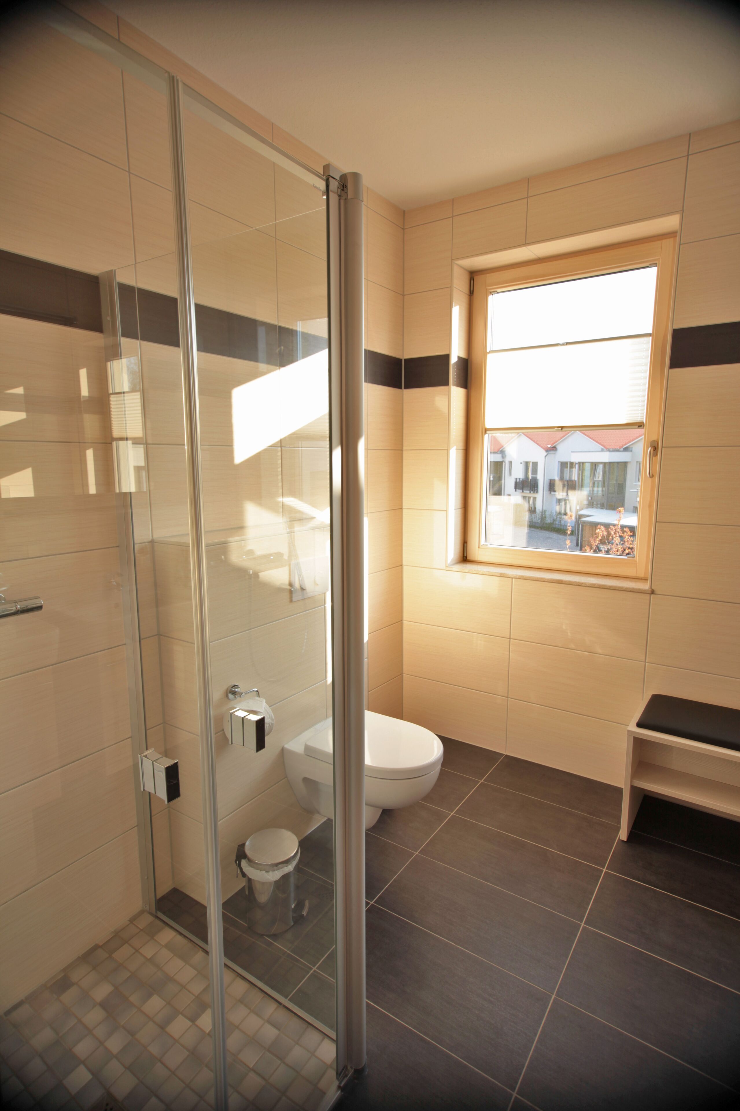Een badkamer met een douchecabine van glas, een toilet en een raam met uitzicht.