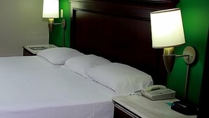 Habitación de hotel con una cama grande, un teléfono en la mesita de noche y una ventana con cortinas.