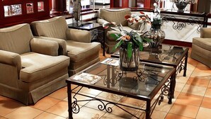 Salón con sofás de cuero, una mesa de centro de vidrio y plantas decorativas.