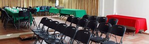 Un salón de conferencias con mesas y sillas, una mesa roja y un telón de fondo.