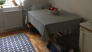 Un dormitorio con cama, mesita de noche, ventana con cortinas, radiador, alfombra estampada y lámpara colgante.