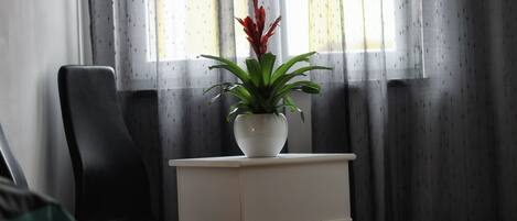 A small white bedside table with a potted plant in a white pot.