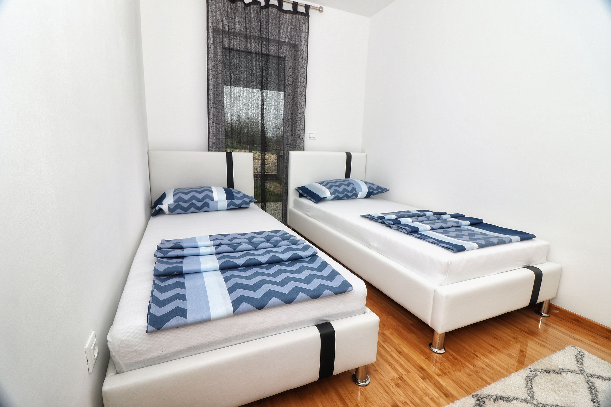 A room with two single beds, each with a white mattress and blue patterned bedding.