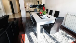 Un comedor moderno con una mesa blanca, sillas negras y una planta en maceta.
