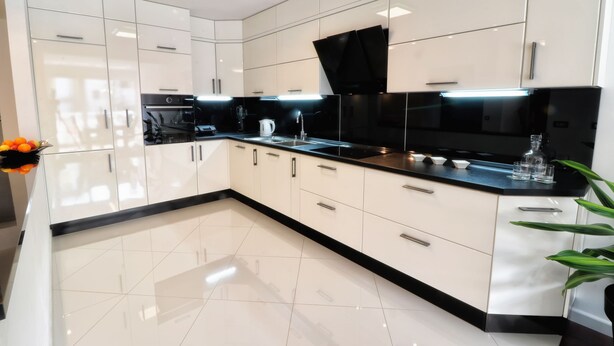 Una cocina moderna con armarios blancos, encimeras negras y una campana extractora negra.