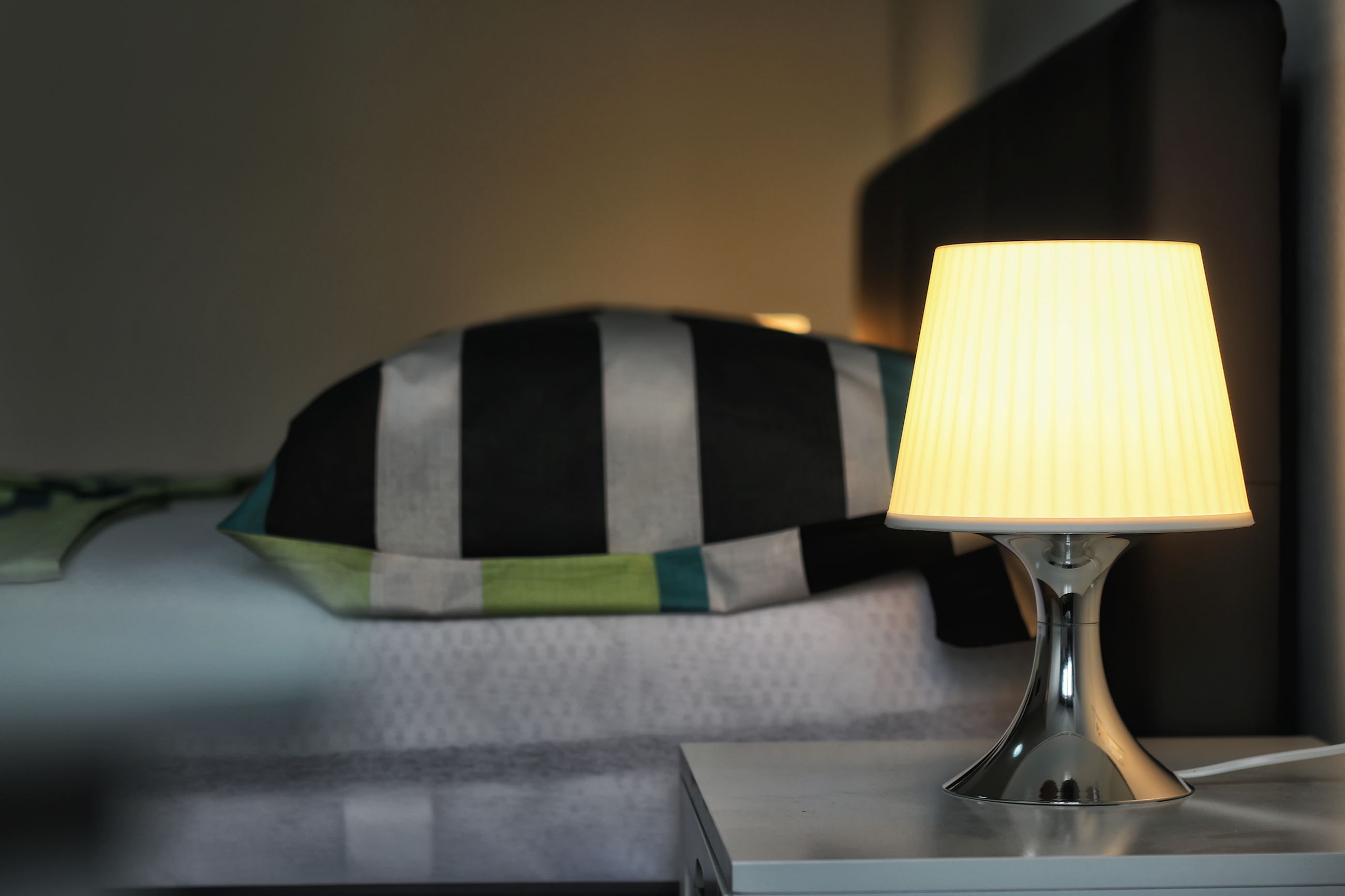 Un comodino con una lampada, un cuscino e un letto in una camera d'hotel.