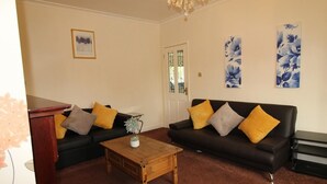 A living room with two sofas, a coffee table, and floral wall art. - Dryden House (Chesterfield)